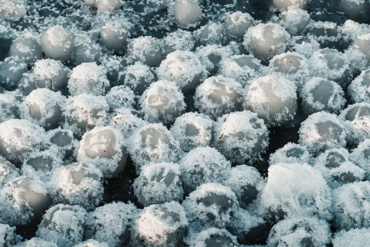 A thick layer of white hailstones piled on the ground after a storm