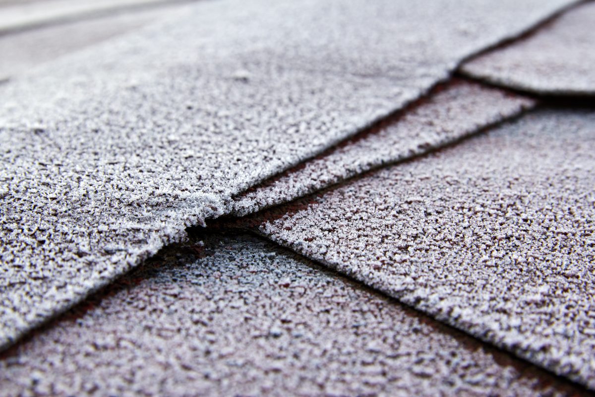 A close view of overlapping asphalt shingles showing the granule surface and the cut edges