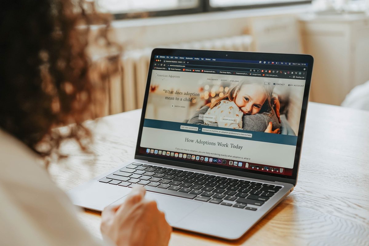 A person at a wooden table browsing a website on a laptop